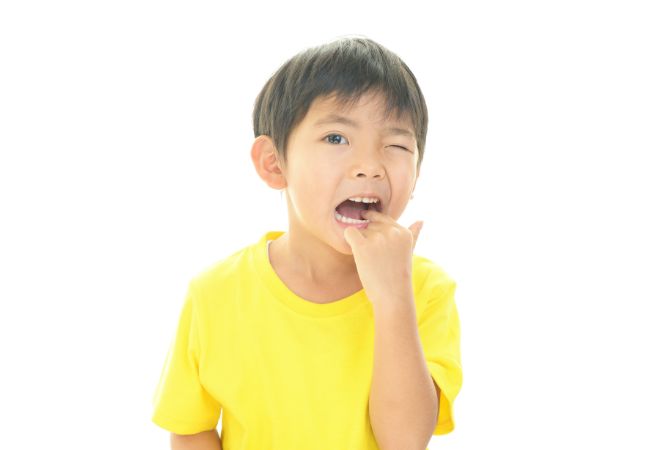 奥歯を触る黄色い服を着た男の子