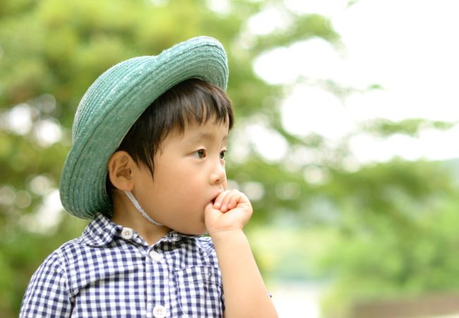 外で自分の指をおしゃぶりする幼児