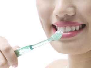 歯ブラシで前歯を磨く女性の口元